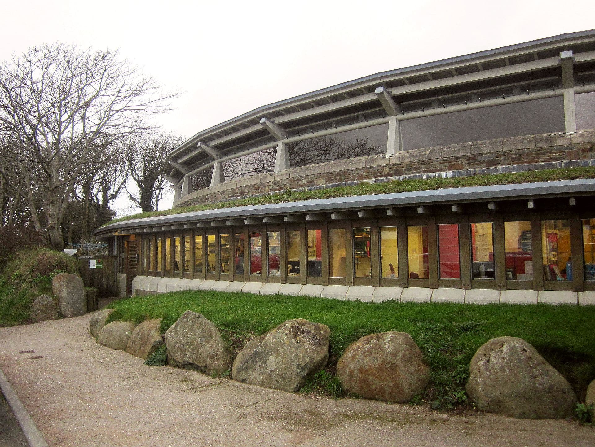 The curved, low-rise Oriel y Parc gallery building with large boulders and grass in front, St Davids