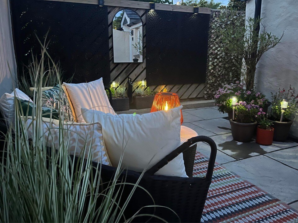 Tŷ Cosy private courtyard at night with lantern and cushioned seating
