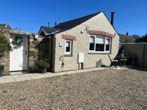 Tŷ Cosy cottage exterior with its parking area on a sunny day in St Davids