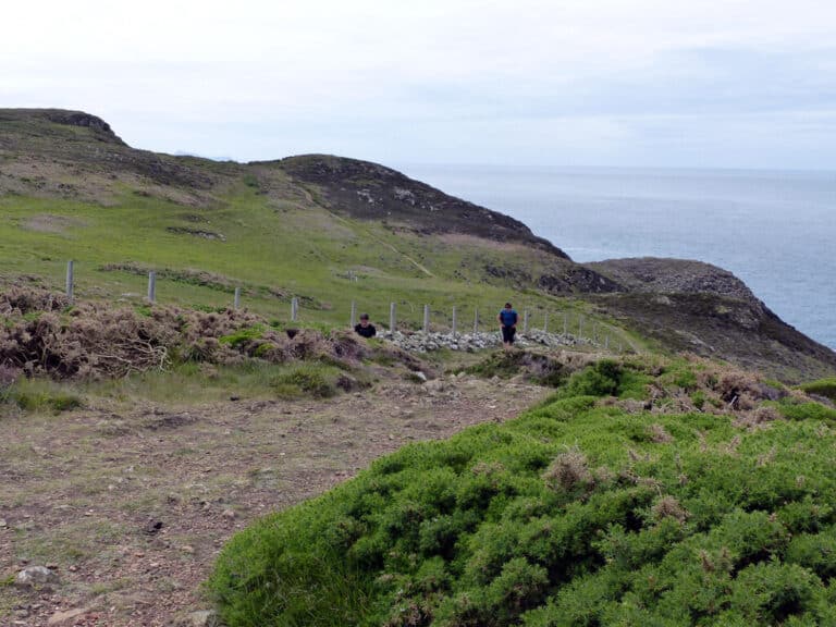 Walkers on the Pembrokeshire Coast Path above the sea, looking west